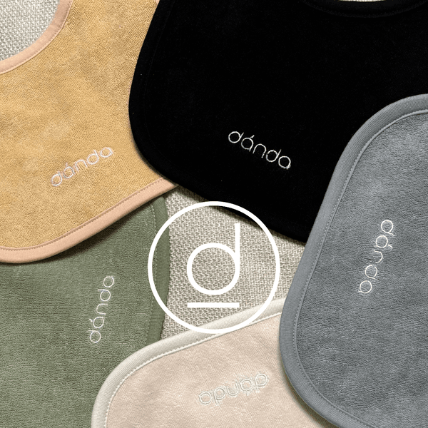 A collection of soft baby bibs featuring the danda logo.