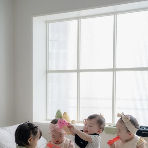 Four adorable babies playing on a white bed.